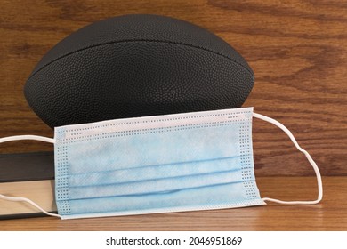 Concept Of School Sports Resuming With  Protection Of Face Masks In Public Health And Safety Recommendations Seen In Black Football, Mask, And Book Symbols 