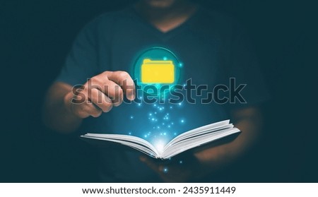 The concept of searching for information for learning and analyzing, Businessman holding magnifying glass with folder icon inside and looking at opened book.