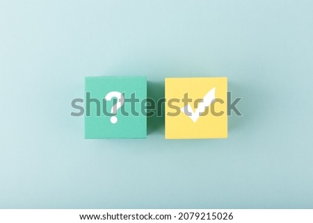 Concept of searching for solution or ideas, doubts, uncertainty and final good result. Question sign and checkmark on yellow and blue toy cubes on bright pastel pink background. 