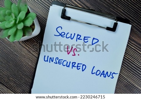 Concept of Secured Vs Unsecured Loans write on paperwork isolated on Wooden Table.
