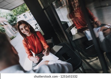 Concept Of Self Presentation And First Meeting. Portrait Of Charming Office Woman Holding Visit Card In Hands While Sitting In Outdoor Cafe With Man