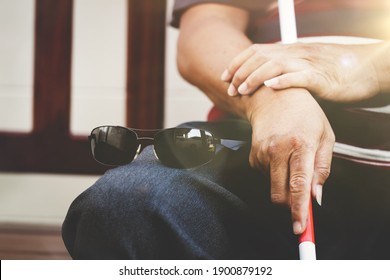 Concept Self-care of a blind disabled man : Self-care of a blind disabled man
A visually impaired man sits on a chair, puts his glasses and sticks on his cane, resting alone in his house.