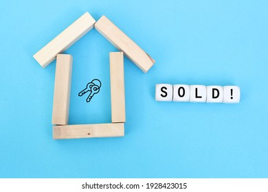 Concept of selling or buying a house or real estate. House symbol made of wooden blocks and sold word on wooden cubes with key icon. - Shutterstock ID 1928423015