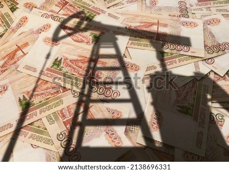 concept of selling minerals for Russian rubles. The shadow of the oil rig against the background of Russian money. Earn money from mining gas and oil energy resources