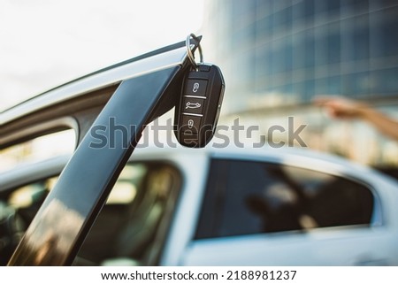 The concept of selling the purchase of leasing or renting a new car. Close-up of a car key hanging on the edge of an open vehicle door