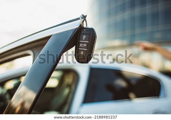 The concept of selling the purchase of leasing or\
renting a new car. Close-up of a car key hanging on the edge of an\
open vehicle door