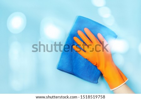 The concept of service cleaning. Hand in rubber glove wipes blue surface.