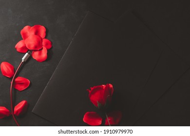 Concept shape, love, technology Red smartphone charging cable and rose petals on black background - Powered by Shutterstock