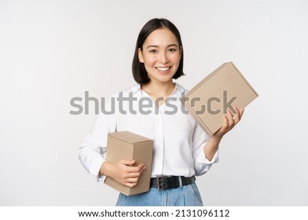 Concept of shopping and delivery. Young happy asian woman posing with boxes and smiling, standing over white background