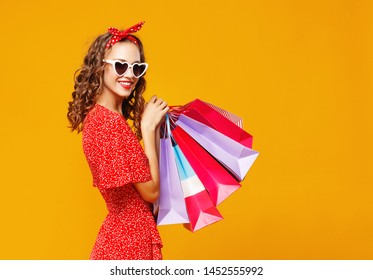 concept of shopping purchases and sales of happy young girl with packages   on yellow background