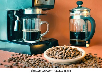 Concept Shot Of Coffee Expresso Maker With Glass Mug Amd Cofee Beans In Front On Orange Background 