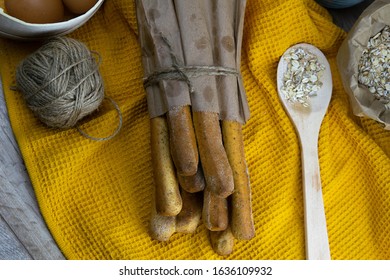 Concept Shot Of Spice Bread Sticks With A Wooden Spoon On The Wood Table, Oatmeal And A Skein Of Bag Thread. Front Views