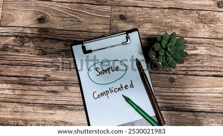 Concept of Simple or Complicated write on paperwork isolated on wooden background.