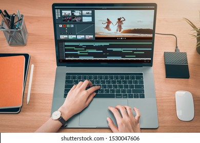 Concept of simple operation of blogger and vlogger, hand using laptop on video editor works with footage on wooden table, camera and accessories on table. - Powered by Shutterstock