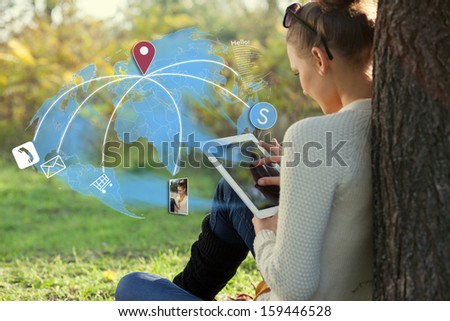 Concept of sitting young woman using her tablet pc during rest in the park