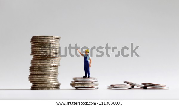 The concept of\
a social gap between labor and wages.\
The stack of coins with miniature people.