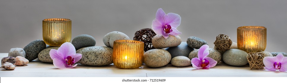 Wellness-Konzept, Massage, Yoga, Wohlbefinden oder Feng Shui mit mineralischen Kieselsteinen, frischen orchiden Blumen und Kerzen, Panoramabildleben