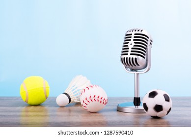 Concept Sports Commentator : The Retro Microphone Put On The Wooden Table With Football Or Soccer , Tennis Ball , Baseball And Shuttlecock Isolated On Blue Background