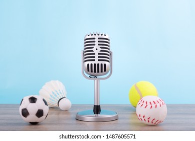 Concept Sports Commentator : The Retro Microphone Put On The Wooden Table With Football Or Soccer , Tennis Ball , Baseball And Shuttlecock Isolated On Blue Background