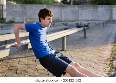 concept of sports and health - teen boy training and pushups at the stadium. Physical exercise. Workout, fitness and health care.
