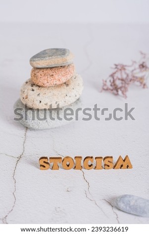 Concept of stoicism wooden letters on the background of a pyramid of stones  vertical view