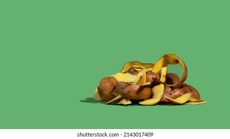 Concept Of Stop Food Waste Day. Potato Peels Are One Of The Most Commonly Discarded Items During Food Prep. Green Background.