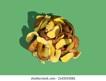 Concept of Stop food waste day. Potato peels are one of the most commonly discarded items during food prep. Green background.