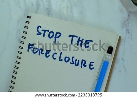 Concept of Stop The Foreclosure write on a book isolated on Wooden Table.