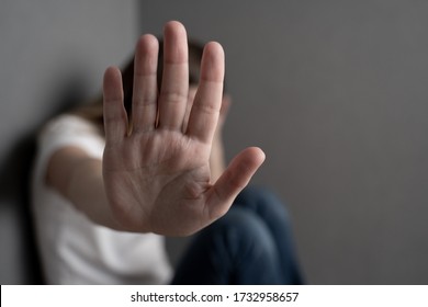 Concept of stop to gender violence. Woman sitting on the floor has her arm stretched out and the palm of her hand open making the stop gesture. - Shutterstock ID 1732958657
