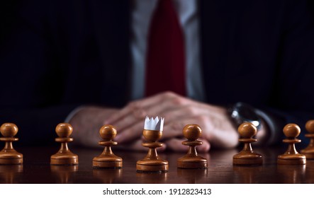 das Konzept der Strategie und der Geschäftsplanung, ein Geschäftsmann auf einem Schachbrett vor ausgekleideten weißen Pfoten, von denen einer in einer Papierkrone, Strategie und Taktik, Bereitschaft zum Kampf ist.