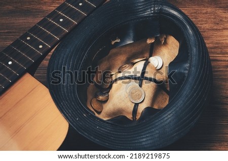 The concept of a street musician beggar. Hat with coins and a guitar. View from above.