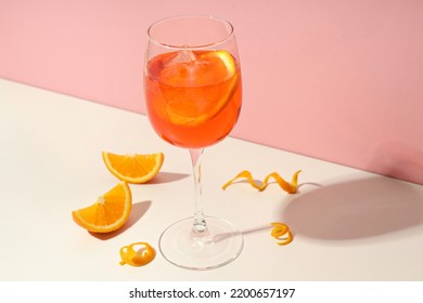 Concept of summer cocktail, Aperol Spritz on white table against pink background