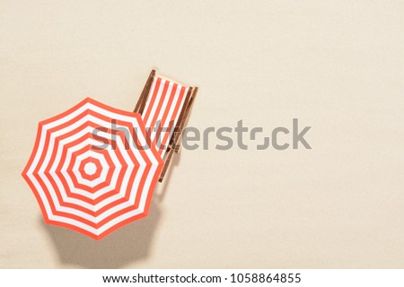 The concept of summer vacation. Top view on a sun lounger under an umbrella on the sandy beach