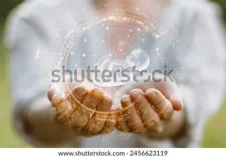 Concept of support for human embryo during pregnancy. Supports the embryo with his hands on a blurred background.