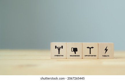 Concept of SWOT analysis and strategic planning technique. Strengths, weaknesses, threats and opportunities of company. SWOT symbols on wooden cubes with beautiful grey background and copy space.