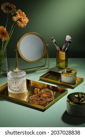 Concept Table With Gold Tray And Luxury Jewelry Jar And Mirror, Flower, Makeup Brushes On Beige Background With Light On The Wall