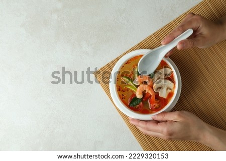 Concept of tasty eating with Tom yum soup on white textured background