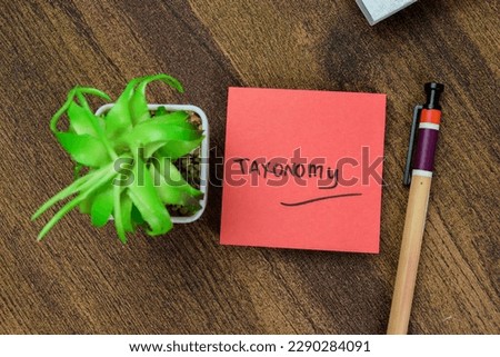Concept of Taxonomy write on sticky notes isolated on Wooden Table.