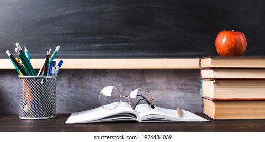 Concept to teacher's day. Pens, apple, pencils, books and glasses on the table, against the background of chalkboard. Back to school, copy space. - Powered by Shutterstock