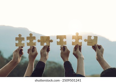 Concept of teamwork and partnership. Business teamwork joins puzzle pieces into the sky with sunrise. Charity, volunteer. Unity, team business. Team building, synergy or collaboration.business goals.