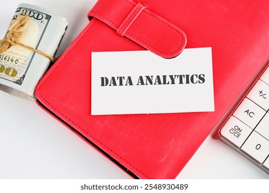 The concept of technology and development. Phrase, words, text DATA ANALYTICS on a white business card on the background of a red notebook.