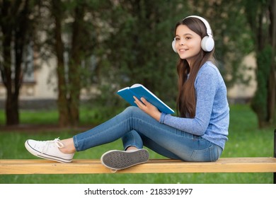 Concept Of Teen. Happy Teen Girl Reading And Listening To Audiobook In Headphones