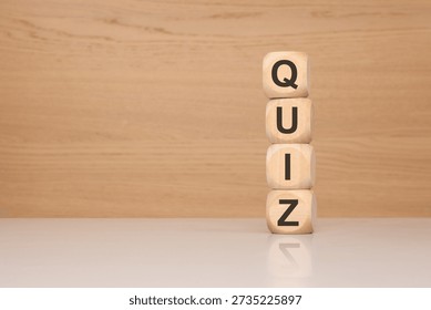 Concept of testing, education, and knowledge evaluation. Four wooden blocks stacked vertically to form the word QUIZ in a bright office setting. Perfect for e-learning, academic exams, trivia, and employee assessment themes.