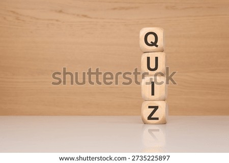 Concept of testing, education, and knowledge evaluation. Four wooden blocks stacked vertically to form the word QUIZ in a bright office setting. Perfect for e-learning, academic exams, trivia, and employee assessment themes.