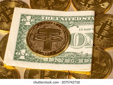 Concept of Tether coin against gold bitcoin coins and a single US dollar note or bill. Tether is backed by US dollar and used for trading in alt coins