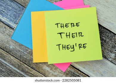 Concept of There, Their, They're write on sticky notes isolated on Wooden Table.