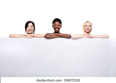 Concept With Three Different Ethnicity Women, Asian, Afro American And Caucasian, Over A White Empty Panel With Free Space Smiling And Looking Naked Isolated