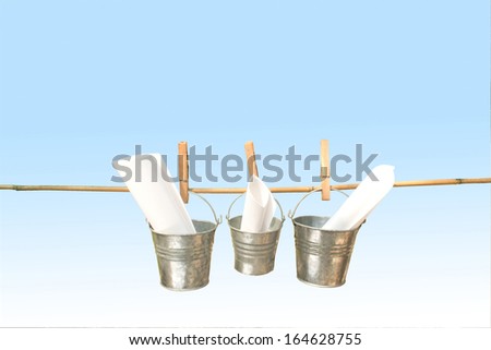 concept three galvanized buckets pegged on bamboo stick with blue background