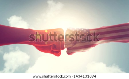 Concept of trade war between USA and China. Two fists hitting each other over sky background and sunlight with copy space.