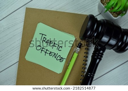 Concept of Traffic Offence write on sticky notes with gavel isolated on Wooden Table.